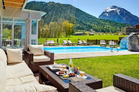 Outdoor pool in the garden with large sunbathing area and comfortable garden furniture