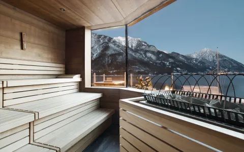 Moderne Sauna mit großer Glasfassade und Blick auf den Achensee und die verschneiten Berge