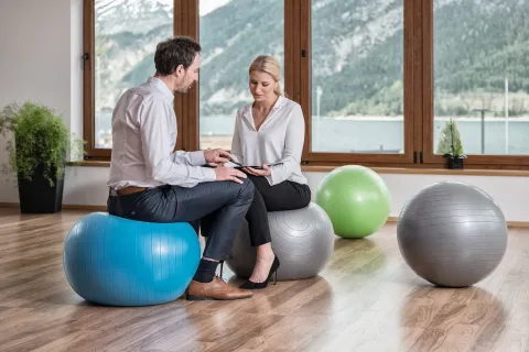 Frau und Mann auf Gymnastikbällen während eines Seminars