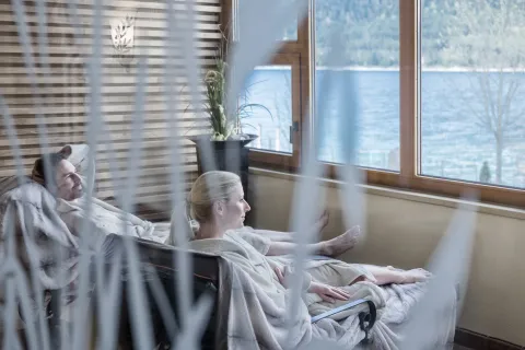 Couple relaxing in bathrobes and blankets with a view of the lake in summer