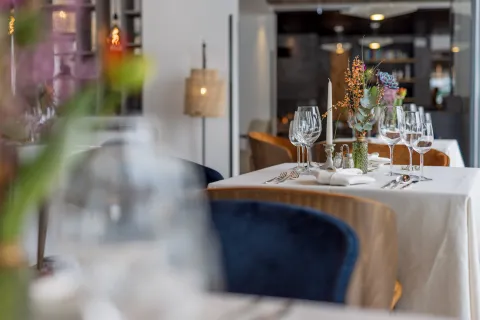 Festlich gedeckter Tisch im Restaurant mit Weingläsern, Kerzenständer und Blumenschmuck