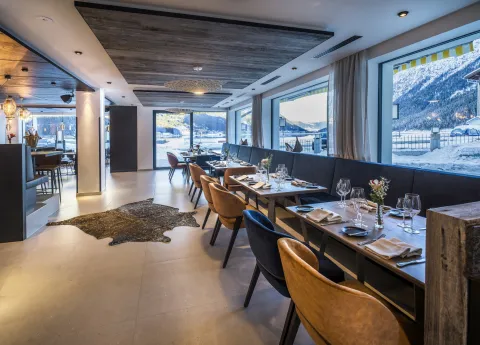 Restaurant mit gedeckten Tischen und moderner Bar mit Aussicht auf den Achensee im Winter