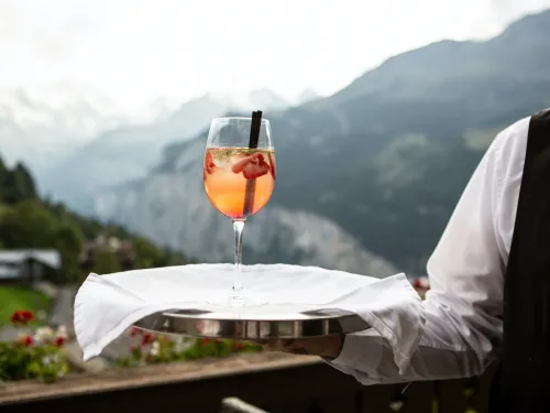 Oranger Cocktail mit Erdbeeren und Minze auf einem Tablett in den Bergen