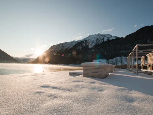 Blick vom Steg auf den dampfenden Achensee im Winter am Morgen