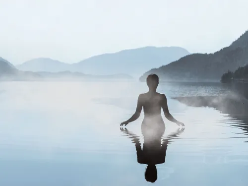 Frau badet in einem ruhigen See in den Bergen bei Nebel